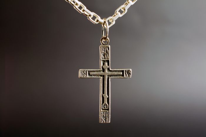 christian cross on a silver chain, faith, spirituality and religion concept. selective focus, dark blurred background