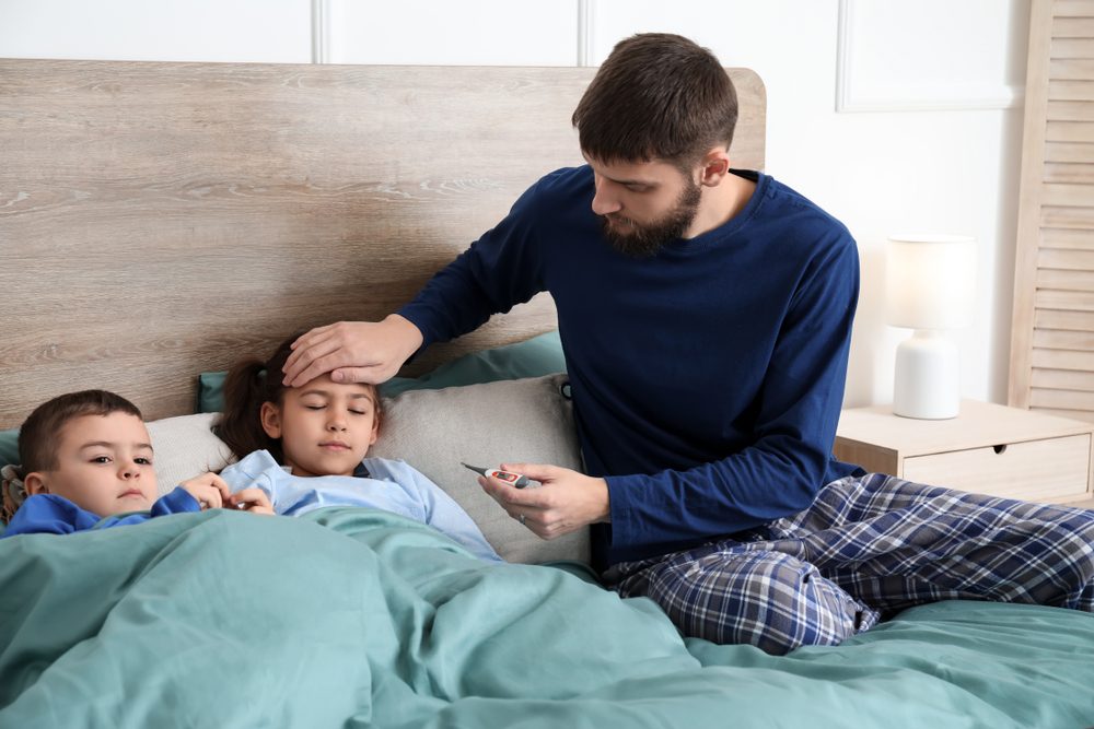 Young father taking care of sick children at home