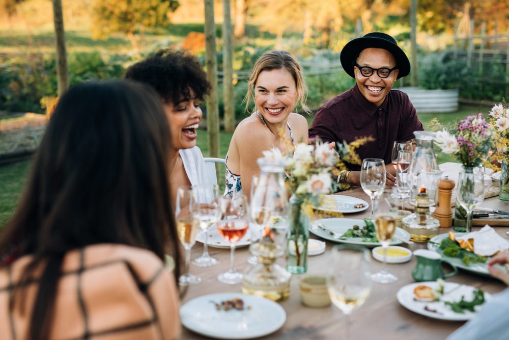 Group of friends enjoying outdoor party in home garden. Millennials  enjoying summer meal at restaurant.