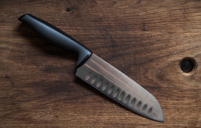 The knife lies on the old wooden surface. Knife Santoku. Professional chef's knife.