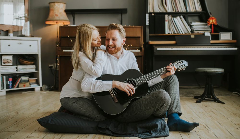 Lovely young couple playing guitar in the room