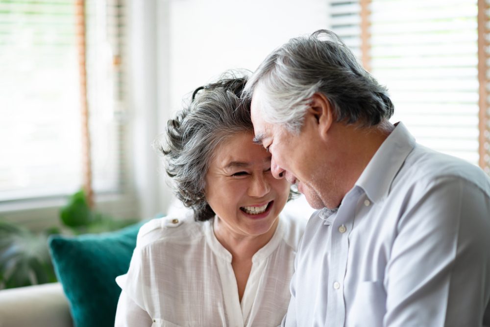 Asian senior couple in love laughing and having fun at their house. Anniversary. Copy space.