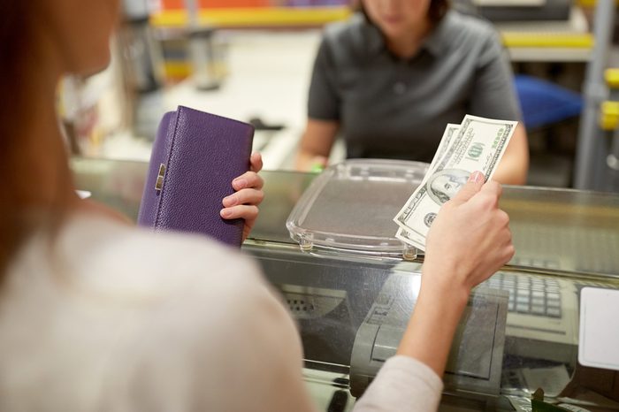 shopping, payment, consumerism and people concept - woman paying money and cashier at store cash register