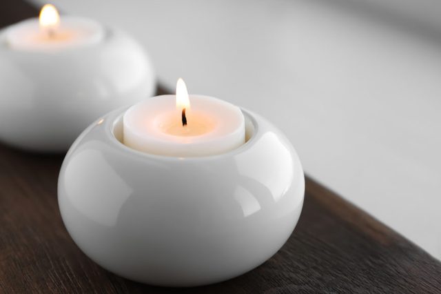 Beautiful burning wax candle in holder on table