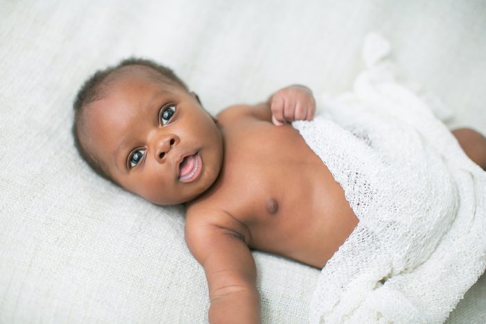 Awake Newborn Baby on Cream White Background