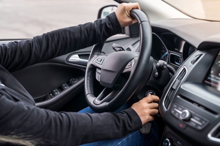 Female hands on steering wheel starting a car