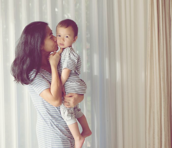 Young Asian mother is kissing her lovely one year old son. Vintage photo mom and son
