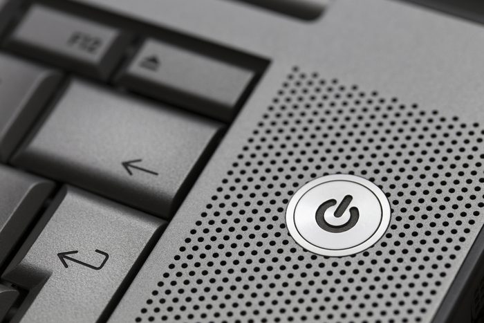 Closeup of silver computer laptop selective focus on standby on button ideal for technology business start power energy symbol.