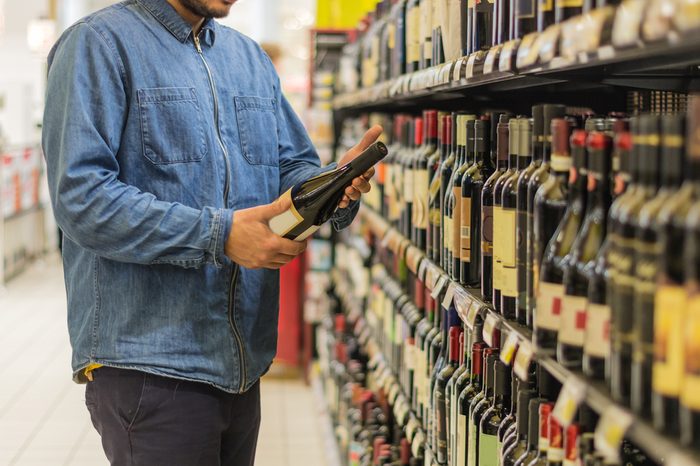 Man is buying a bottle of wine at the supermarket.