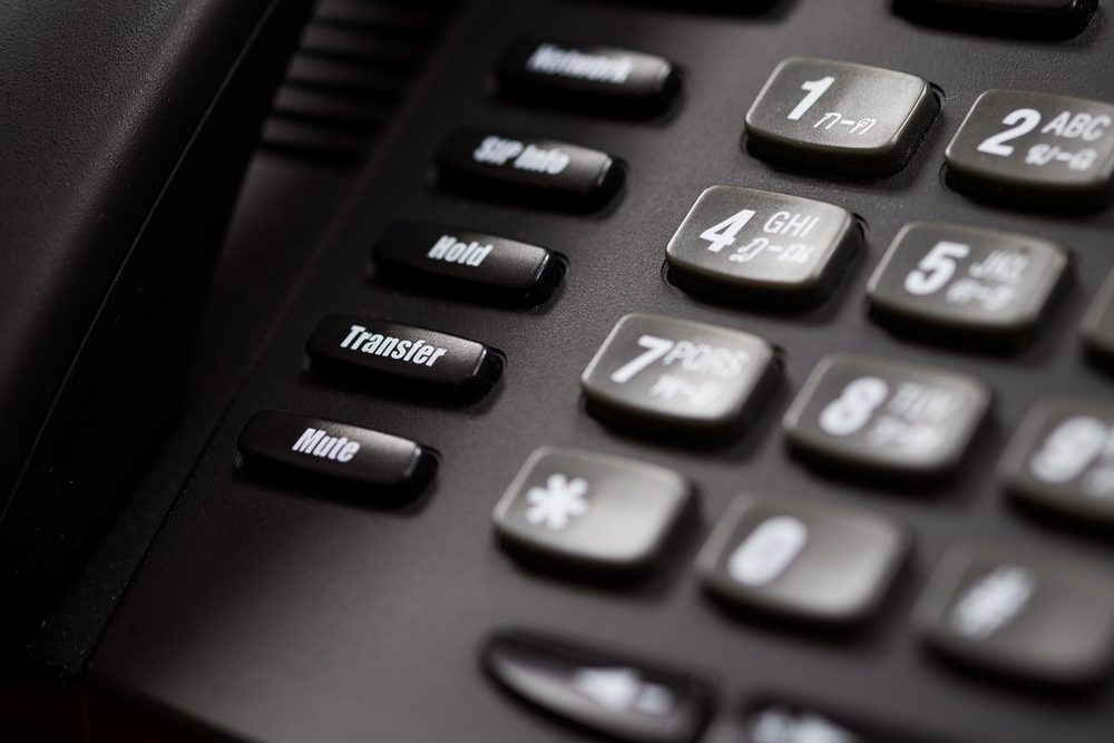 A close up of a Black office IP Phone on a desk