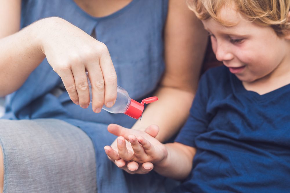 Mother and son using wash hand sanitizer gel pump dispenser.