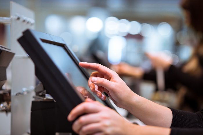 Young woman hand doing process payment on a touchscreen cash register, finance concept (color toned image)