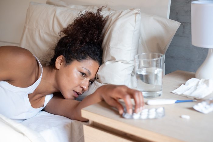 Portrait of black sick woman taking medications