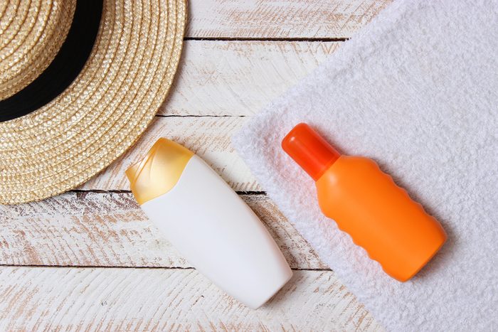 sunscreen, towel, hat, glasses on a wooden background. minimalism, the top view, flatlay