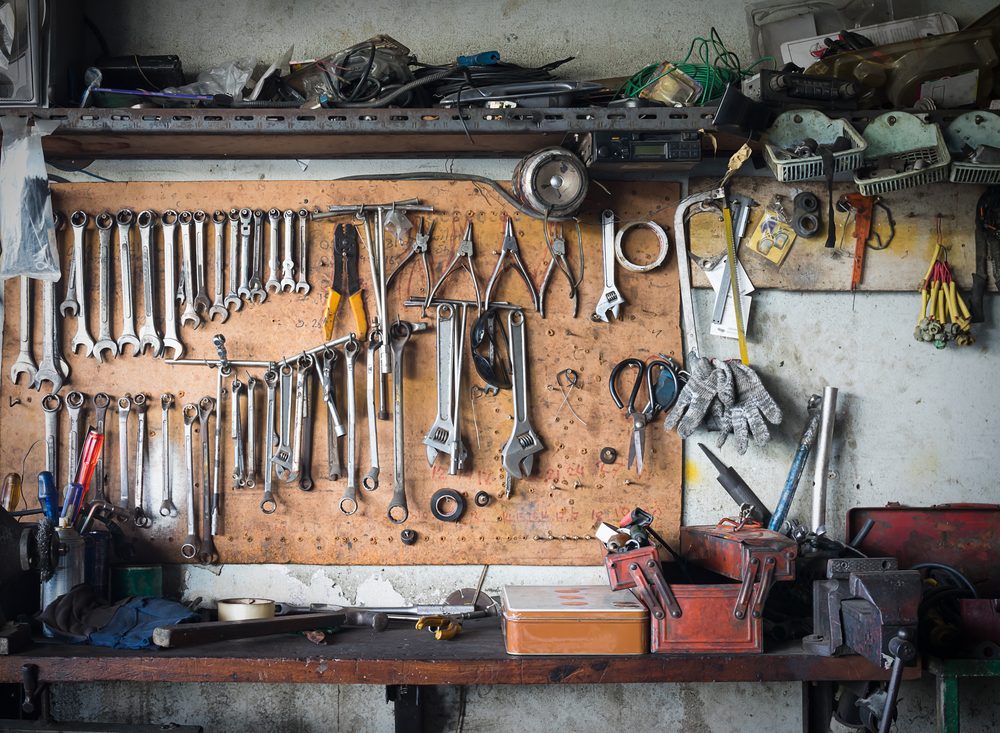 Old tools hanging on wall in workshop , Tool shelf against a wall