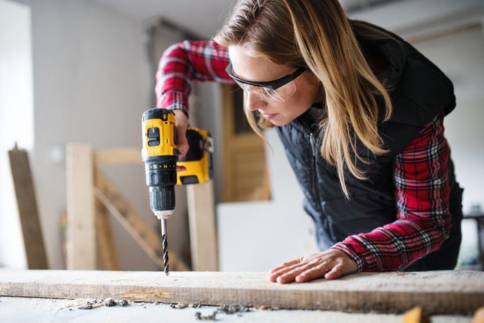 Young woman worker in the carpenter workroom.