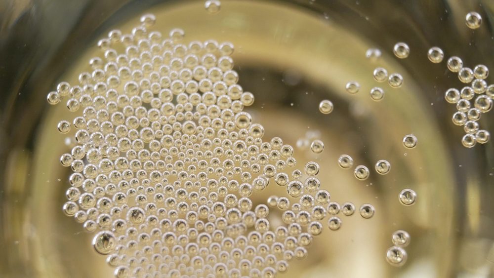 Many small bubbles in a glass. Champagne pouring and foaming over holiday. Christmas celebrating concept