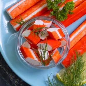 Imitation Crab sticks on a blue plate, with some pieces in a bowl on the plate