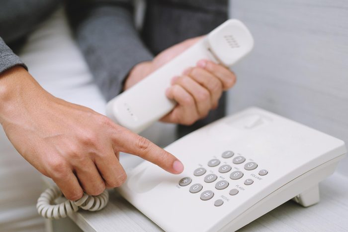 On the phone book a room : Young man calling talking on the telephone while lying bedroom on hotel.