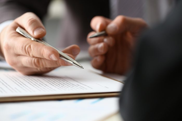 Male arm in suit and tie fill form clipped pad with silver pen closeup. Sign gesture read pact sale agent bank job make note loan credit mortgage investment finance executive chief legal teamwork law