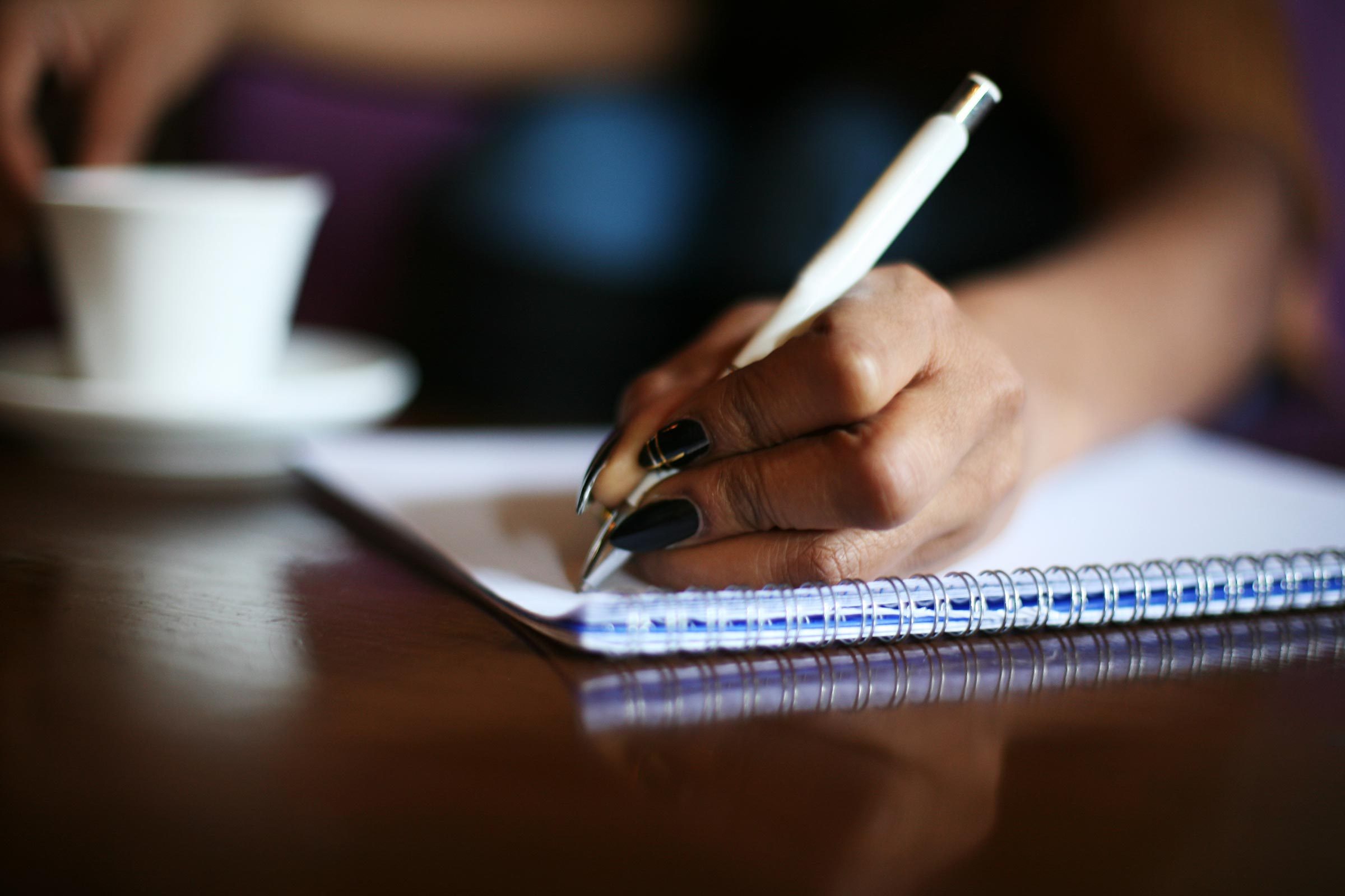 Focus on woman hands writing in notes.