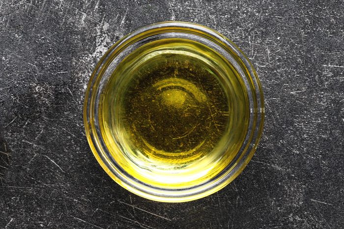 Glass bowl with olive oil on dark background