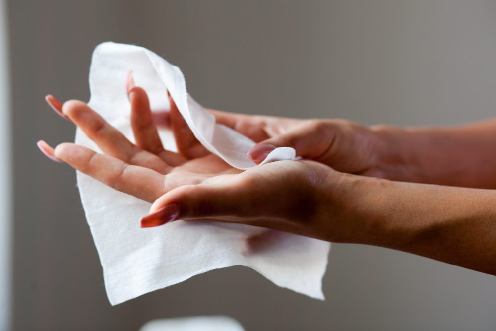 Young woman cleaning hands with wet wipes