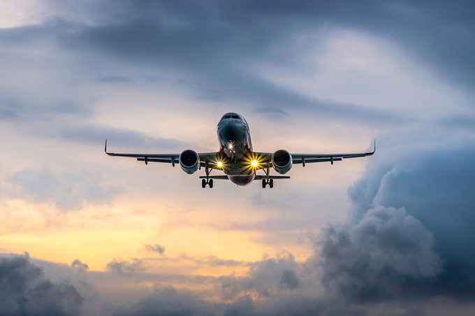 Airplane flying in dramatic sunset