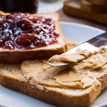 Peanut butter and raspberry jelly sandwich on wooden background. Perfect sweet breakfast. Close up.