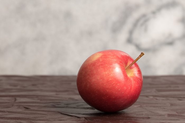 Isolated red mcintosh apple on wooden surface with clear marble background