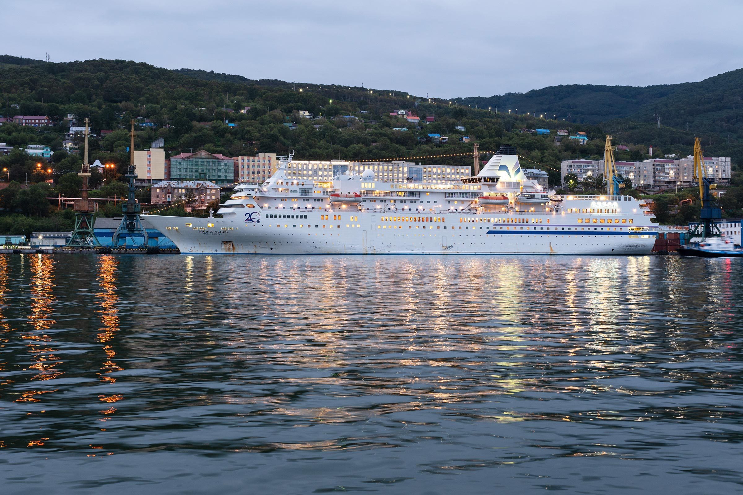 AVACHA BAY, KAMCHATKA PENINSULA, RUSSIAN FAR EAST - 4 SEPTEMBER, 2018: Picturesque night view of white Japanese cruise liner Pacific Venus anchored at pier in Petropavlovsk-Kamchatsky Seaport.