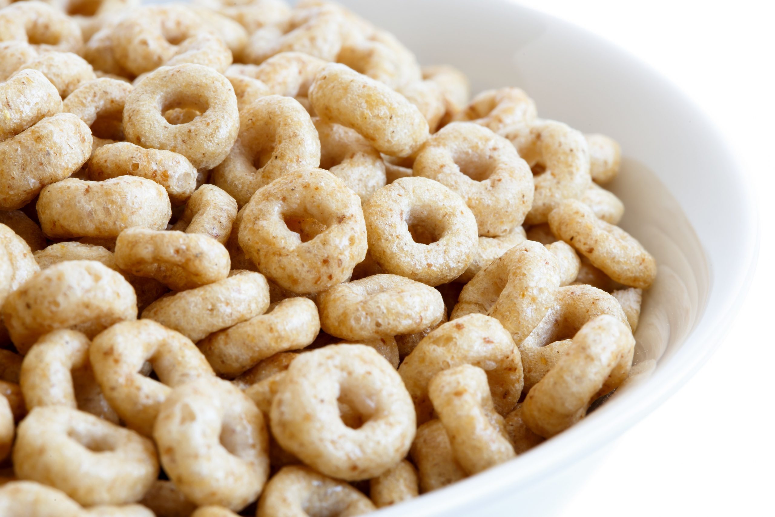 Detail of bowl of honey cheerios on white.