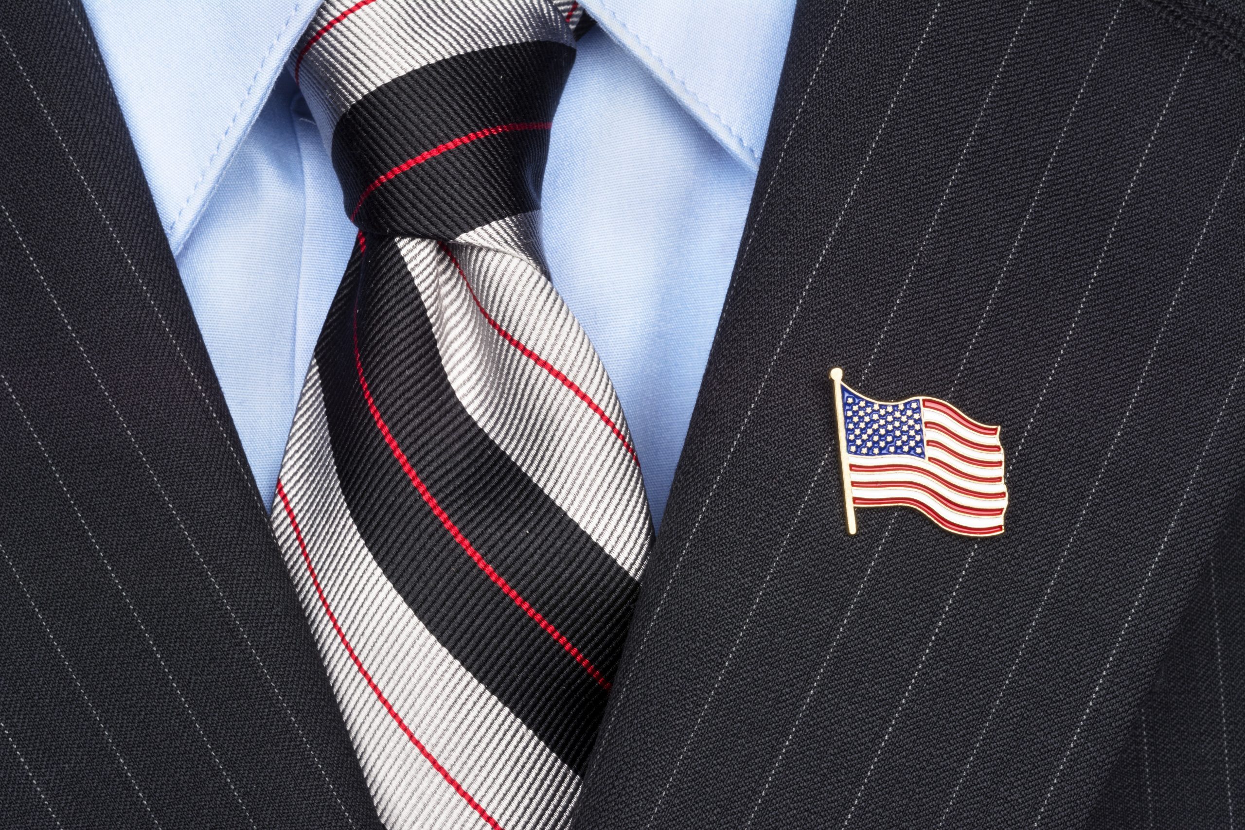 A symbolic American flag lapel pin on the collar of a businessman's suit