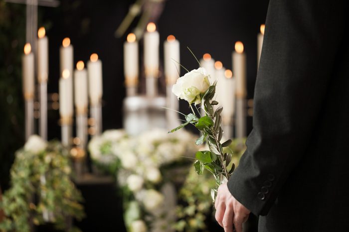 Religion, death and dolor - man at funeral with white rose mourning the dead