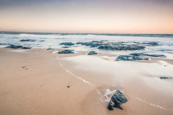 Rough sea and golden sand at the rugged coast in jeffrey's bay,South Africa. This is the most famous location for surfing in africa ,