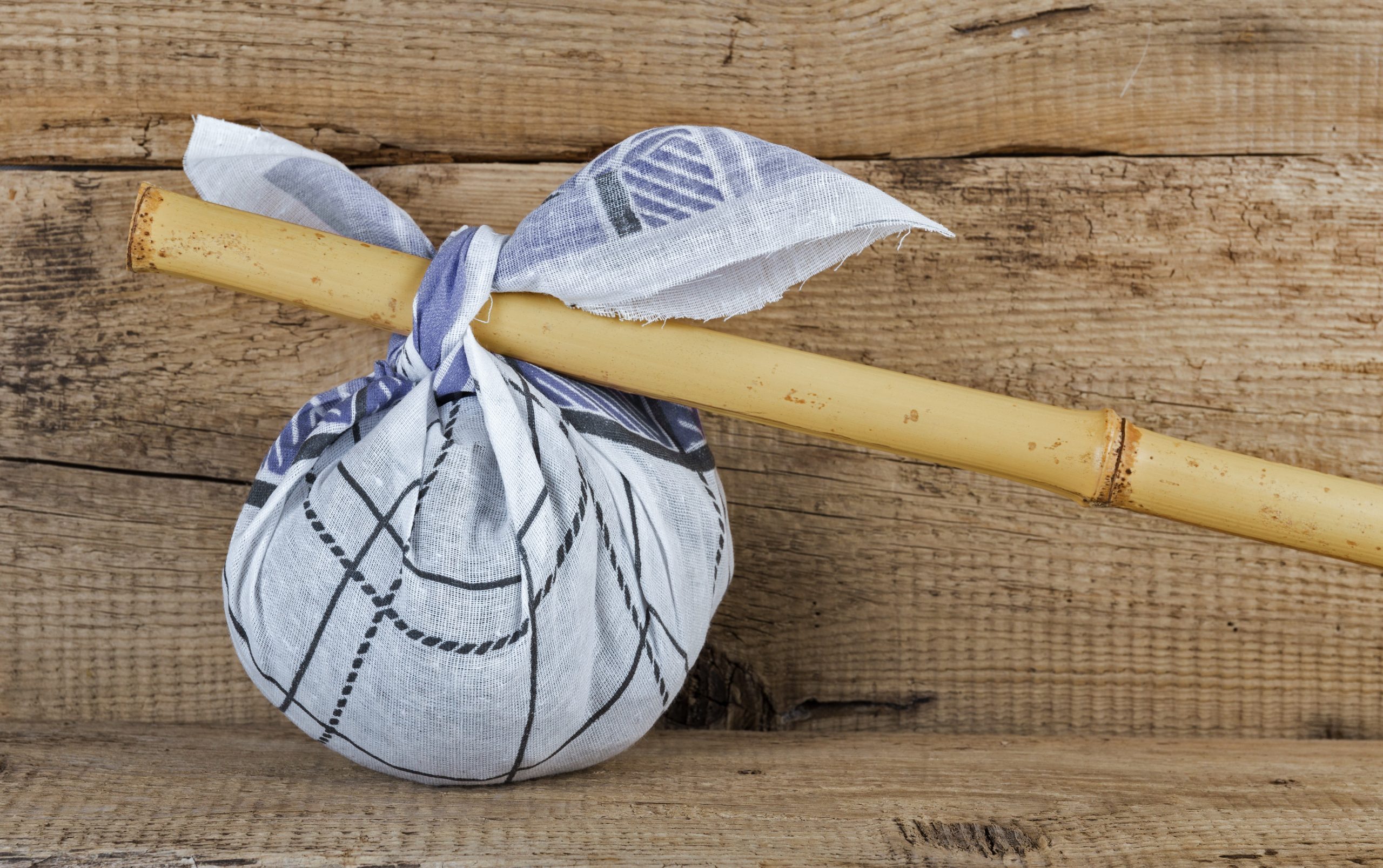 Rural knapsack on a bamboo pole on a old wooden background