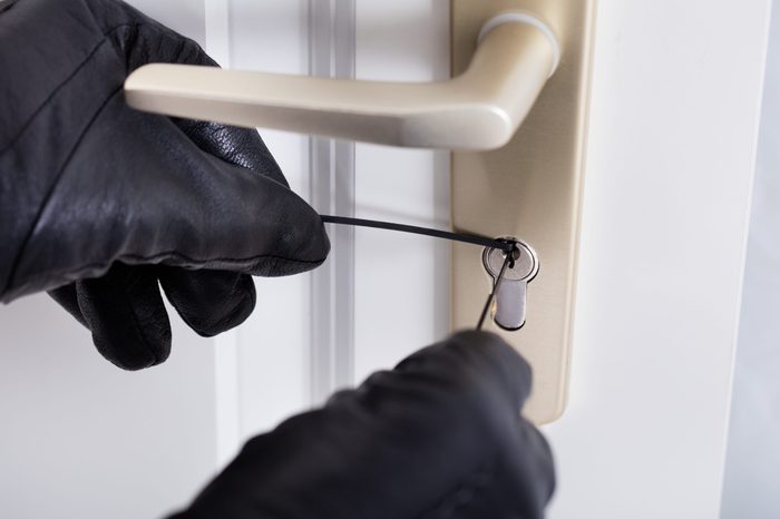 Close-up Of A Burglar With Gloves Picking Lock