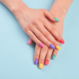 Female beautiful manicured hands. Woman hands with stylish colorful nails on light blue background. Skin and nail care.