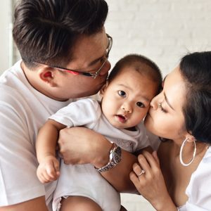 Asian woman and man kissing their baby with love.Mother and Father with lovely son.Happy family concept in house.Love and relationship idea.Warmness and happiness.Parent with little boy.