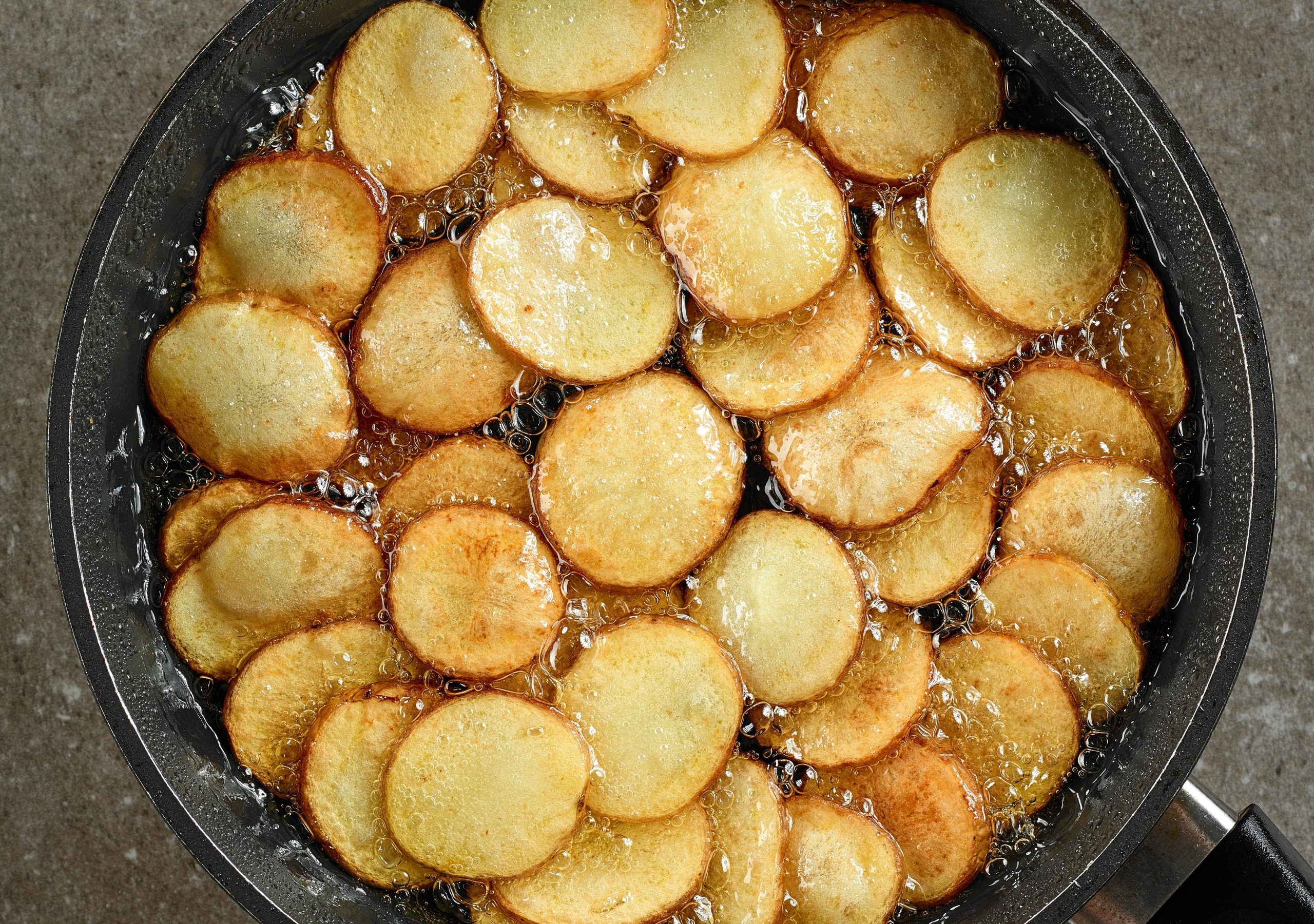 frying potatoes in pan with oil, top view