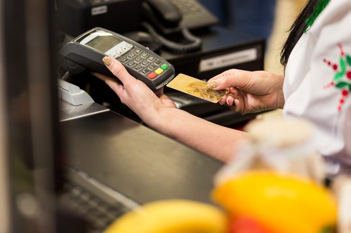 Woman hand with credit card swipe through terminal for sale, in market. Shopping and retail concept