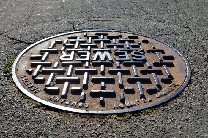 Sewer metal cap/cover on the road under shade in close up