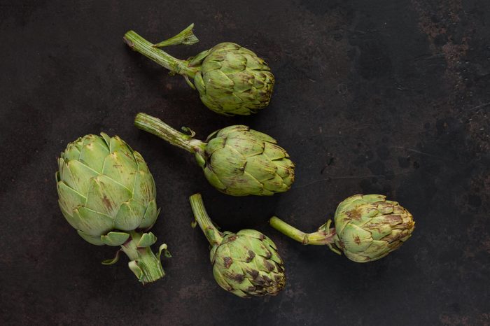 Close up photo of fresh artichoke. Top view on dark background.