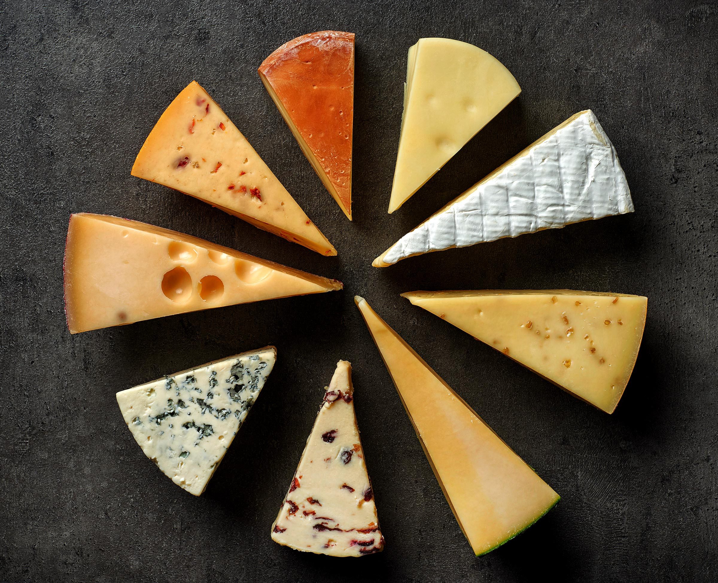 various types of cheese on black kitchen table, top view