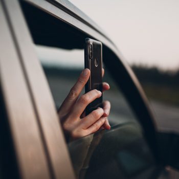 Girl takes pictures on the phone from the car window