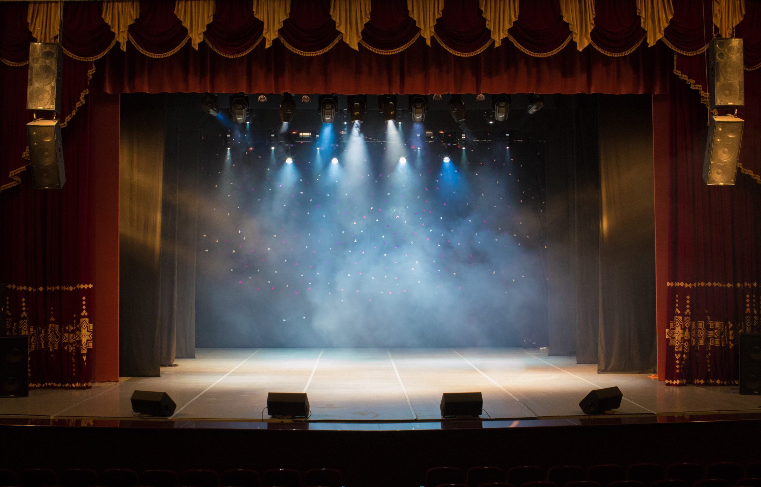 An empty stage of the theater, lit by spotlights and smoke before the performance