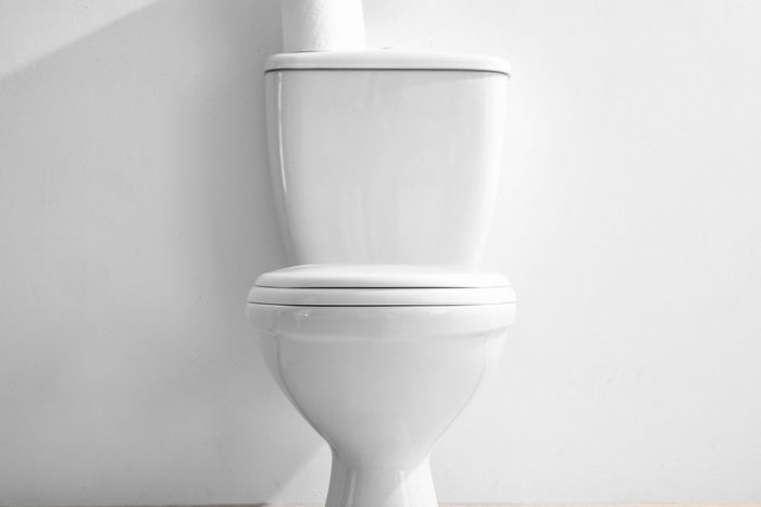 New ceramic toilet bowl near light wall