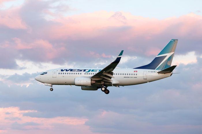 Toronto Pearson Airport, Canada - May 15 2019: close view of West Jet airlines Boeing 737-700 airplane landing / taking off from runway tarmac. Aircraft industry and air transport travel concept.