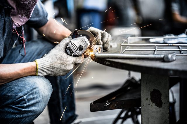 Asian worker making sparks while welding steel