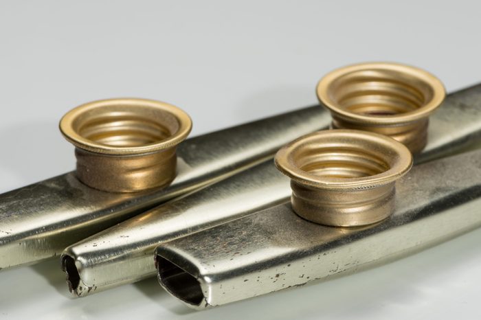 Closeup of metal kazoos on a white reflective surface